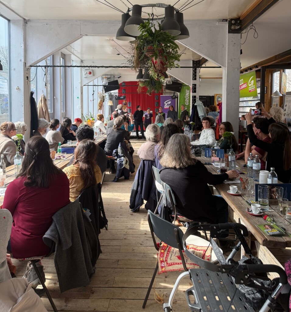 Badeschiff Wien: Gäste an Tischen, im Hintergrund singen gerade Frauen des Chors "Frauen singen für Befreiung"