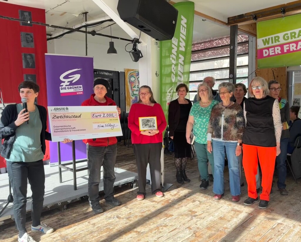 Nina Nöhrig überreicht das Preisgeld für die "Frau des Jahres" in Form eines sehr großen Kartonschecks an die Obfrau der "Österreichischen Lagergemeinschaft Ravensbrück und ihre Freund:innen", daneben weitere Mitglieder des Vereins