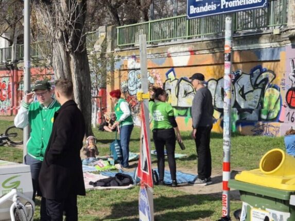 Menschen am Donaukanal vor einer mit Graffiti bemalten Mauer