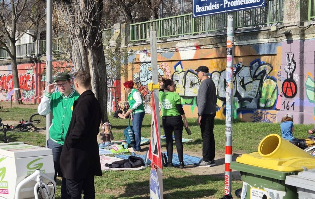 Menschen am Donaukanal vor einer mit Graffiti bemalten Mauer