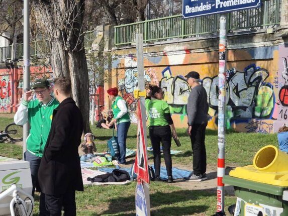 Menschen am Donaukanal vor einer mit Graffiti bemalten Mauer